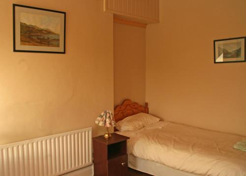 a bedroom with a bed and a table with a flower on it at Castlehouse B&B in Renvyle