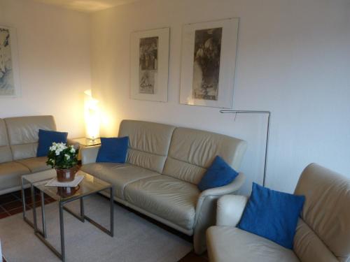 ein Wohnzimmer mit 2 Sofas und einem Tisch mit blauen Kissen in der Unterkunft Appartement Kayser Sylt in Morsum