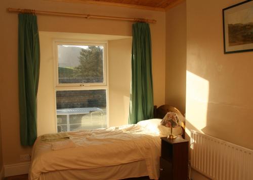 a bedroom with a bed and a window with green curtains at Castlehouse B&B in Renvyle