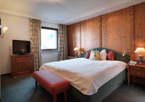 a bedroom with a large bed and a television at Hotel Zürserhof in Zürs am Arlberg