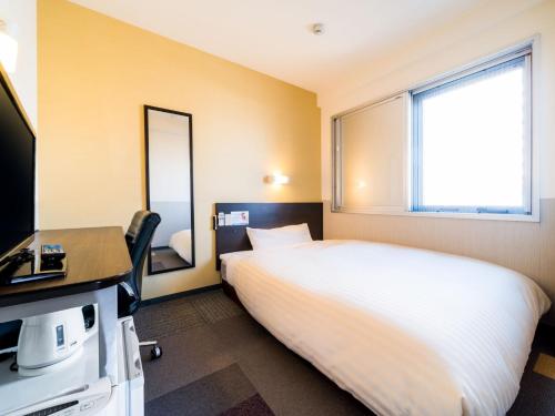 a bedroom with a bed and a desk and a television at Super Hotel Fuji Inter in Fuji