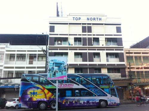 
a double decker bus parked in front of a building at Topnorth Hotel Maesai in Mae Sai
