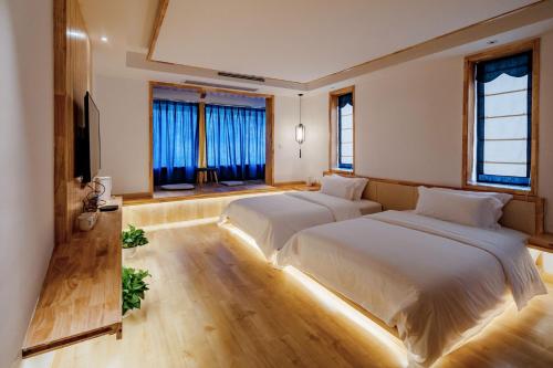 two beds in a room with two windows at Zhangjiajie Su Xin Resort Near Tianmen Shan & Hehua airport-Free pick up in Zhangjiajie