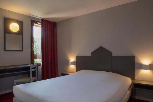 Un dormitorio con una gran cama blanca y una ventana en The Originals City, Hôtel Amys, Tarbes Sud (Inter-Hotel), en Odos