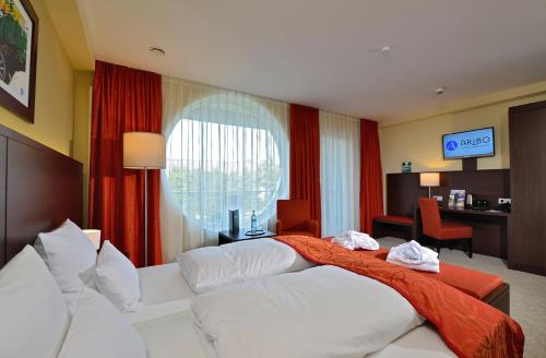 a hotel room with two beds and a desk at Aribo Hotel in Erbendorf