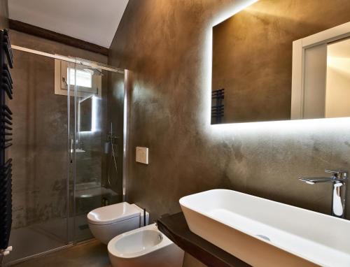 een badkamer met een wastafel, een toilet en een spiegel bij la casa di Veronique in Como