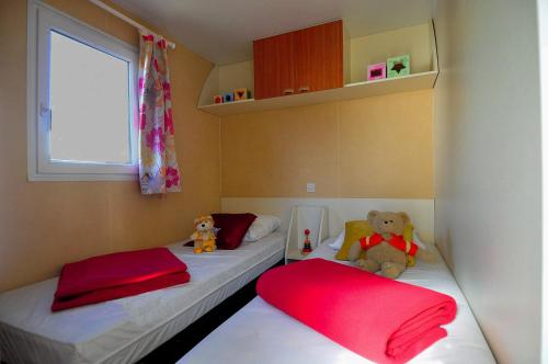 two beds in a small room with a teddy bear on them at Camping La Touesse in Saint-Lunaire