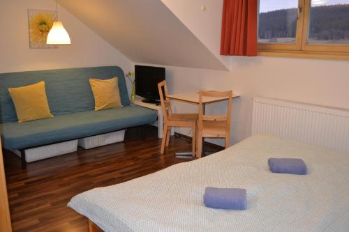 uma sala de estar com duas camas e um sofá em Březník Kilián em Kvilda
