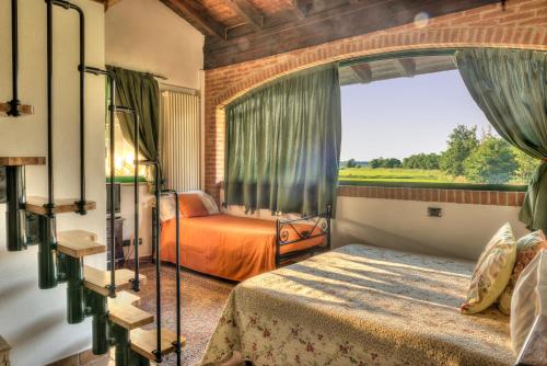 a bedroom with two beds and a large window at Agriturismo Maiocchi in Borgarello