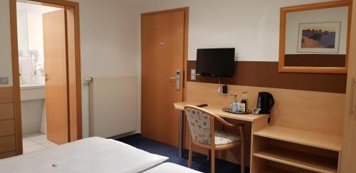 a hotel room with a desk with a television and a bed at Hotel Habana in Aalen