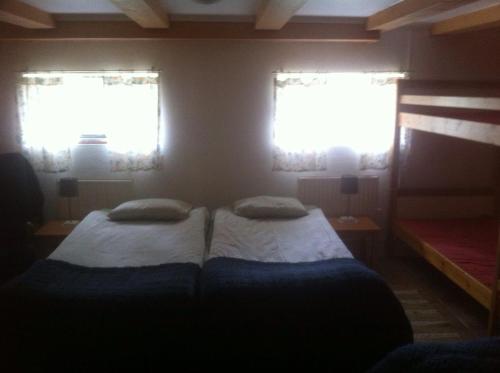 two beds in a small room with two windows at Änggårde B&B in Huse