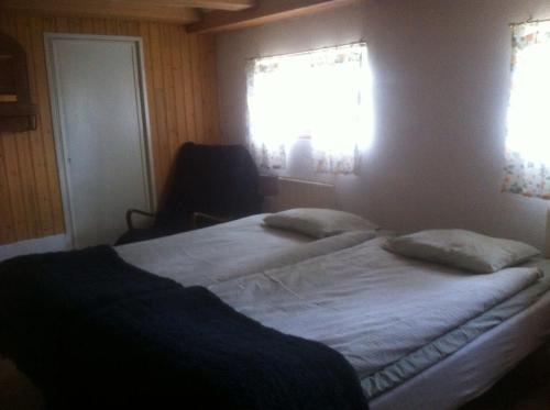 a bedroom with two beds and a window and a chair at Änggårde B&B in Huse
