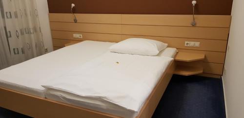 a small bed in a small room with a white bedspread at Hotel Habana in Aalen