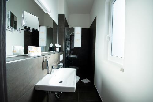 y baño con lavabo blanco y espejo. en V Boutique Hotel Böblingen, en Böblingen