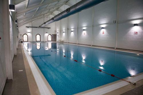 a large indoor swimming pool with blue water at Secret Of Eden Beach House in Filey