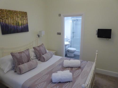 a bedroom with a bed with two pillows and a television at The Osborne Apartments in Torquay