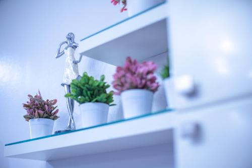 a shelf with potted plants and a cross on it at ARMO Nimman in Chiang Mai