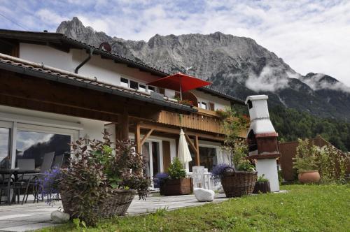 a house with a balcony with a red umbrella at Haus Erli in Mittenwald
