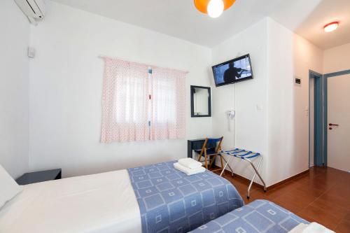 a hotel room with two beds and a television at Fivos Apartments in Aliki