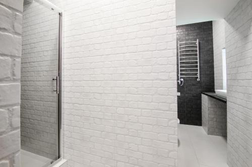 een douche in een badkamer met een witte bakstenen muur bij MyAparts R1 in Lviv