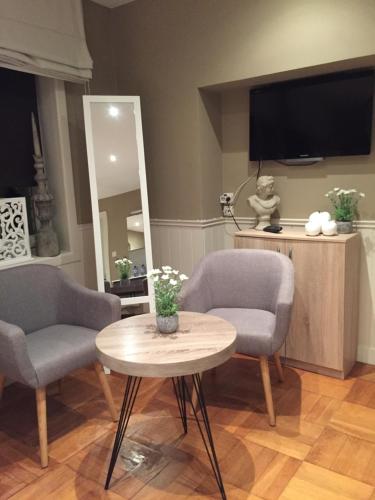 a living room with two chairs and a table and a tv at Huyze-peppins in Maldegem