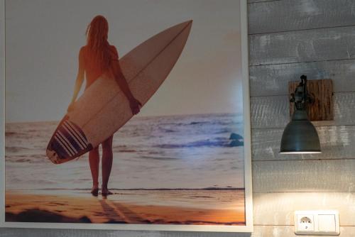 a woman standing on the beach holding a surfboard at Hotel Stadt Cuxhaven in Cuxhaven