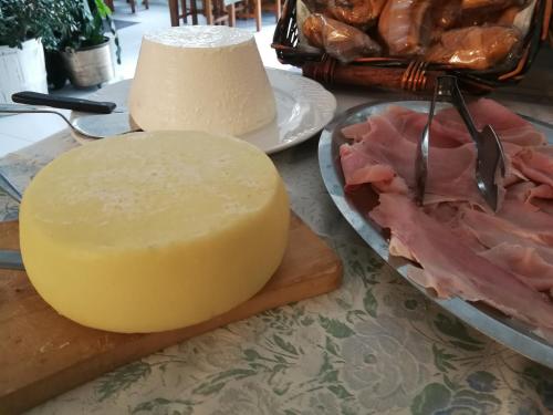 a cheese on a cutting board next to a plate of meat at Albergo Ristorante Belvedere in Minucciano