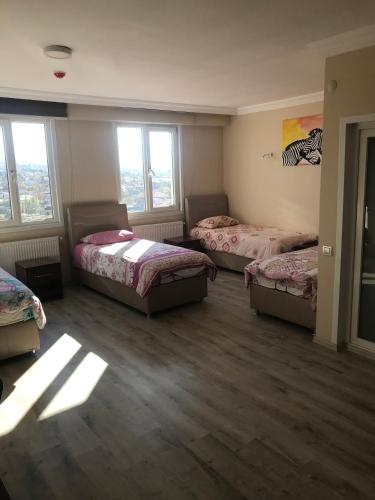 a room with three beds and two windows at Gunes Hotel in Hacıbektaş