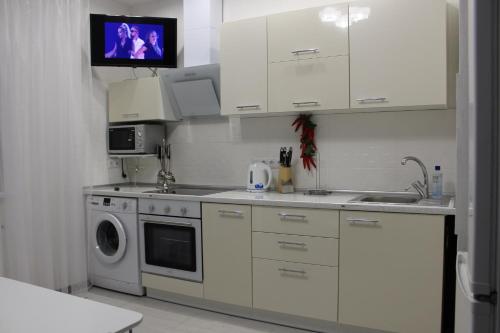 una cucina con armadi bianchi e una lavatrice/asciugatrice di Apartments Butterfly Wing a Odessa