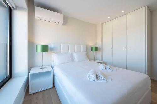 ポルトにあるLovelyStay - Trindade Cozy Apartmentの白いベッドルーム(タオル付きのベッド2台付)
