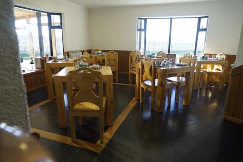 Un comedor con mesas y sillas de madera. en Hostal Doble E Patagonia, en Puerto Natales