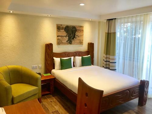 Progressive Park Hotel في نيروبي: غرفة نوم بسرير كبير مع كرسي وكرسي