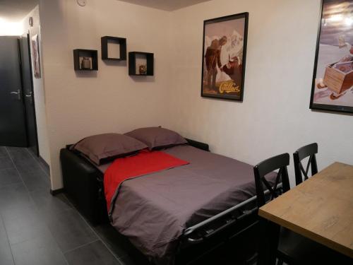 a bed in a room with a table and pictures on the wall at Appartement 4 personnes au pied des pistes du Linga à CHÂTEL in Châtel