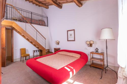 a bedroom with a large red bed and a staircase at Agriturismo diffuso Tenuta Armaiolo - widespread farmhouse in Rapolano Terme