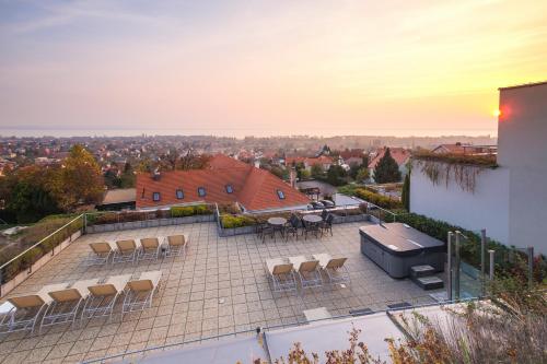 a patio with chairs and a grill on top of a building at Zenit Wellness Hotel Balaton in Vonyarcvashegy