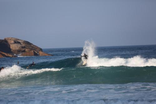 a person riding a wave on a surfboard in the ocean at Kalani Pousada in Praia do Rosa