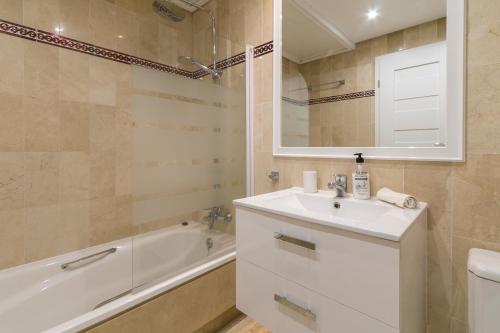 W łazience znajduje się umywalka, wanna i lustro. w obiekcie Costa Del Sol Beach Apartment w mieście Estepona