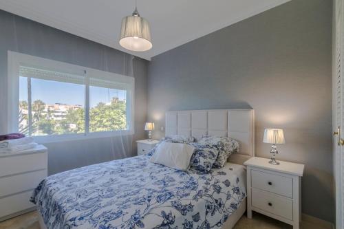 sypialnia z łóżkiem z niebiesko-białą pościelą i oknem w obiekcie Costa Del Sol Beach Apartment w mieście Estepona