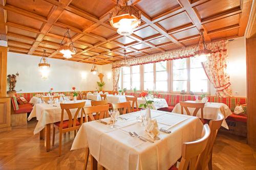 un restaurante con mesas y sillas blancas y ventanas en Hotel Gasthof Engel en Appenweier