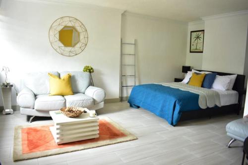 een slaapkamer met een bed en een bank bij Ambleside & Turtle beach towers in Ocho Rios