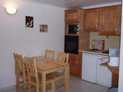 a kitchen with a wooden table and chairs and a table and a kitchen with at L'ancolie in Orelle
