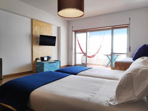 two beds in a room with a large window at Beach & Relax - Studio in Costa da Caparica