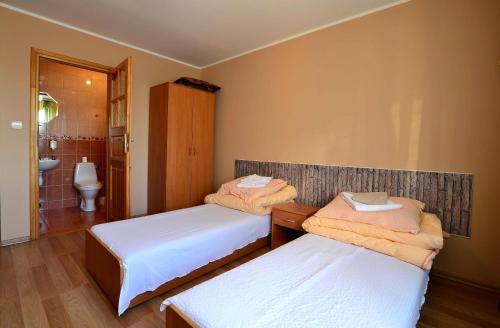 two beds in a room with a bathroom at Zajazd Zagłoba in Widoma