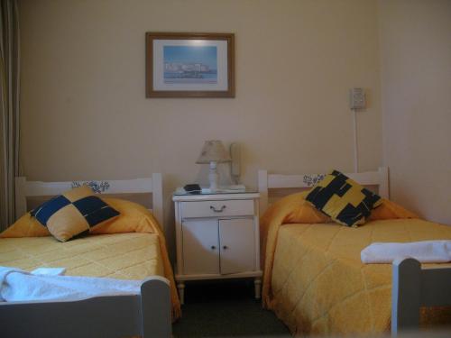 um quarto com duas camas e uma mesa de cabeceira em Posada de la Villa em Villa Gesell