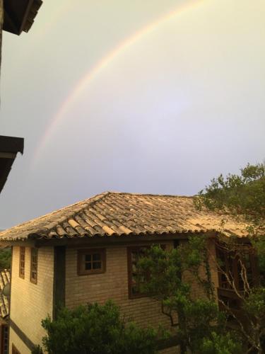 a rainbow in the sky above a house at Pousada Santuário da Madre in Guarda do Embaú