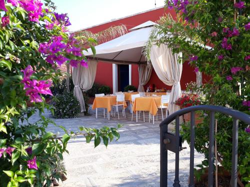 un patio con tavoli, ombrelloni bianchi e fiori di Mediterraneo B&B a Maglie