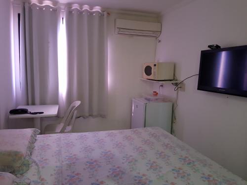 Un dormitorio con una cama y un televisor en la pared. en Apart Porto Jangada Suíte Vista Mar, en Fortaleza