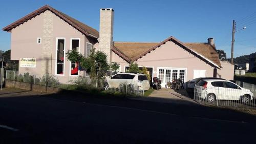 two cars parked in front of a house at Pousada Charme da Serra in Bom Jardim da Serra