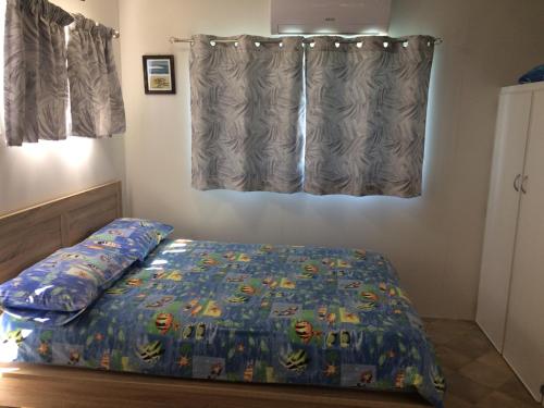 a bedroom with a bed with a comforter and a window at Riviera Caravan Park in Sussex inlet
