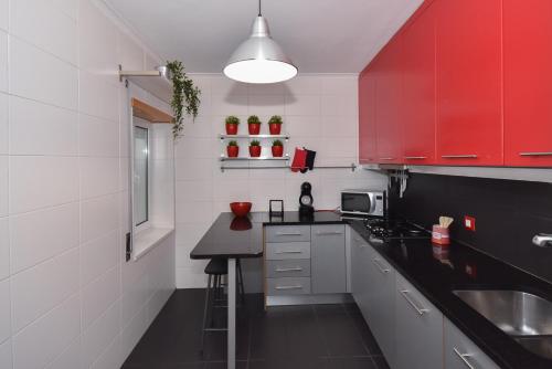 アヴェイロにあるSalineiras Center Apartmentのキッチン(赤いキャビネット、黒いカウンタートップ付)